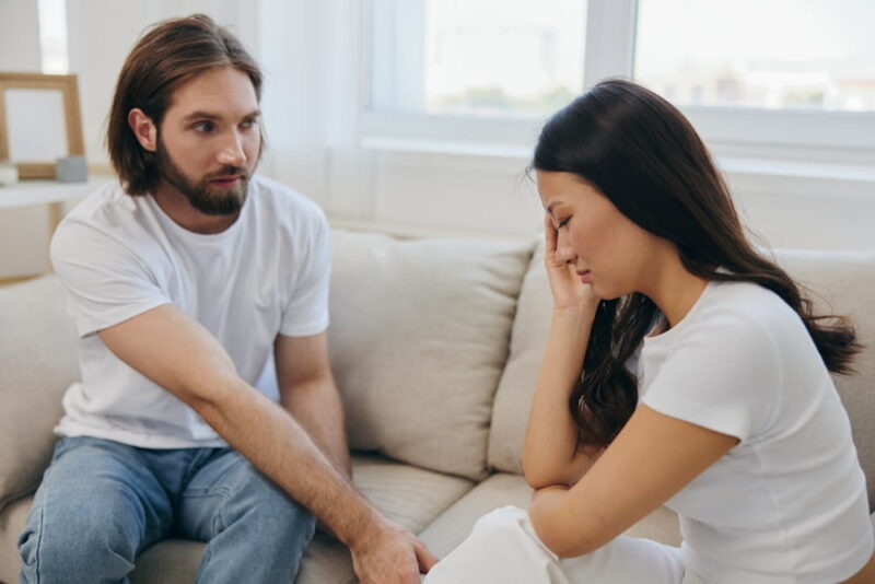 An Asian woman is sad and crying with her male friend at home