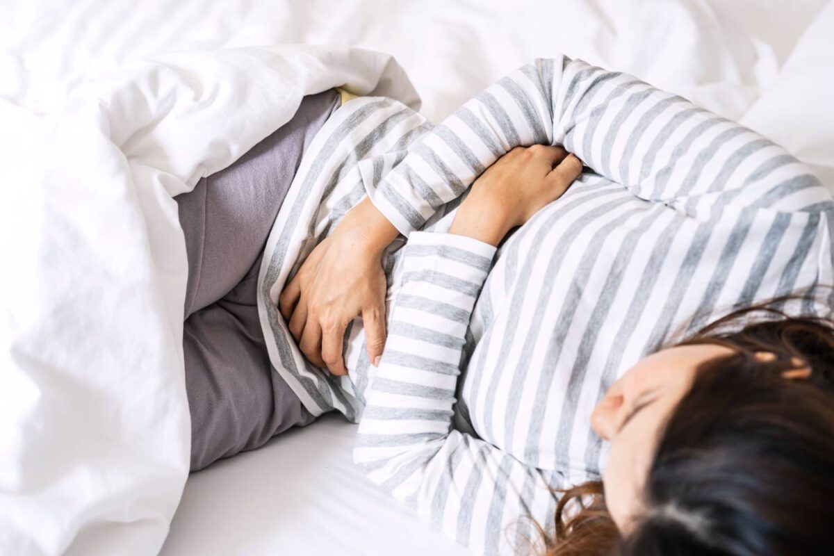 Young woman having stomach ache on the bed